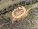 Aerial view of a red dirt race track surrounded by lush forest, offering privacy and recreational opportunity at 7545 Brancy St, Kannapolis, NC 28081