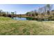 Pond surrounded by grass with lush greenery, and mature trees, creating a peaceful landscape at 7545 Brancy St, Kannapolis, NC 28081