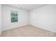 A simple and airy bedroom with neutral carpet and a window that provides natural light at 7730 Woolsey Dr, Gastonia, NC 28056