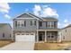 Charming two-story home with gray siding, stone accents, covered porch and two car garage at 7730 Woolsey Dr, Gastonia, NC 28056