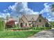 Stunning stone home featuring manicured landscaping and a timeless aesthetic beneath a cloudy, bright blue sky at 1012 Clover Crest Ln, Weddington, NC 28104