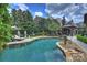 Inviting backyard swimming pool with stone accents, adjacent stone pool house, and verdant landscaping at 1012 Clover Crest Ln, Weddington, NC 28104