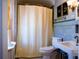 Bathroom featuring blue tiling, a vintage sink, and a shower with a curtain, maintaining a clean and tidy appeal at 1035 Pee Dee Ave, Albemarle, NC 28001