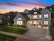 Beautiful two-story home with stone accents, a well-manicured lawn, and a spacious driveway at sunset at 10904 Kilkenny Dr, Matthews, NC 28105