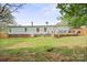 Large, grassy backyard with a cozy deck, complemented by trees and a propane tank, perfect for outdoor living at 115 Oak Creek Rd, Statesville, NC 28625