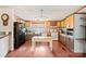 Open kitchen featuring wood cabinets, appliances, light fixture, and an island with butcher block top and wood laminate floors at 115 Oak Creek Rd, Statesville, NC 28625