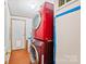A compact laundry area with a stacked washer and dryer, featuring wood-look flooring and access to the exterior at 115 Oak Creek Rd, Statesville, NC 28625