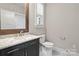Half bath featuring marble countertop, decorative mirror, and toilet next to the window at 13712 Bonnerby Ct, Huntersville, NC 28078