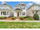Inviting two-story home boasts a covered porch and meticulously maintained landscaping on a sunny day at 13712 Bonnerby Ct, Huntersville, NC 28078