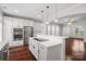 Modern white kitchen featuring stainless steel appliances, a spacious island, and hardwood floors at 13712 Bonnerby Ct, Huntersville, NC 28078