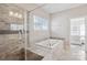 Bathroom features tiled shower with a seamless glass door, large soaking tub, and oversized window at 15402 Country Lake Dr, Pineville, NC 28134