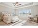 Airy bedroom showcasing tray ceiling, large windows, tufted headboard, and a decorative desk bathed in sunlight at 15402 Country Lake Dr, Pineville, NC 28134