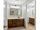 Well-lit bathroom with double vanity, wooden cabinets, large mirror, and neutral tile flooring at 1736 Cavendale Dr, Rock Hill, SC 29732