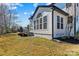 A backyard view of a home featuring a sunroom extension, an outdoor grill, and green lawn at 1840 Sapona Ct, Denver, NC 28037