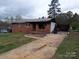 Exterior view of a single-story brick home showcasing its front yard and cracked driveway at 1842 Quail Run Dr, Kingstown, NC 28150