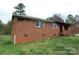 Side exterior view of a single-story brick home with red shutters, set against a grassy lawn at 1842 Quail Run Dr, Kingstown, NC 28150