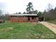 Exterior view of a single-story brick home featuring a metal roof and a spacious front yard at 1842 Quail Run Dr, Kingstown, NC 28150