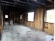 Stripped interior view showcasing a room's wall studs, window openings, and concrete floor at 1842 Quail Run Dr, Kingstown, NC 28150