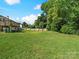 Large, grassy backyard featuring a wooden deck, mature trees, and privacy fence at 2633 N Sharon Amity Rd, Charlotte, NC 28205