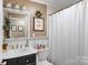 Bright bathroom with black vanity, white sink, framed art, toilet, and shower with white curtain at 2792 Lakeshore Rd, Denver, NC 28037