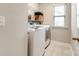 Functional laundry room with white washer and dryer, window, and shelving for storage at 3021 Patchwork Ct, Fort Mill, SC 29708