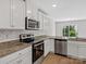 Well-lit kitchen boasts stainless steel appliances, white cabinets, and granite countertops, enhancing its modern appeal at 3034 Trailblazer St, Charlotte, NC 28215