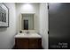 Stylish powder room with a wood vanity, white countertop, and modern mirror at 4609 Hedgemore Dr # I, Charlotte, NC 28209