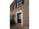 Close-up of a brick home's front door, showcasing its classic white trim and inviting entrance, set against the textured brick at 4609 Hedgemore Dr # I, Charlotte, NC 28209