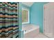 Bright bathroom showcasing a soaking tub with a window view and colorful striped shower curtain at 5519 Burning Ridge Dr, Monroe, NC 28110