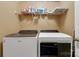 Efficient laundry area with washer and dryer, storage shelves, and neutral wall color at 5519 Burning Ridge Dr, Monroe, NC 28110