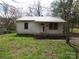 Modest single-story home featuring metal roof and mature trees in front yard at 605 W Elm St, Shelby, NC 28150