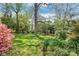Lush backyard with mature trees, vibrant flowers, and playhouses, ideal for outdoor adventures and play at 6100 Rose Valley Dr, Charlotte, NC 28210