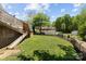 Sloping backyard with a well-maintained lawn, black fencing, and a deck overlooking the yard at 1008 Autumn Ln, Concord, NC 28025