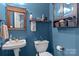 Bathroom featuring blue walls, toilet, sink with wood framed mirror and medicine cabinet at 1008 Autumn Ln, Concord, NC 28025