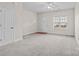 Bright living room featuring neutral walls, plush carpeting, ceiling fan, and a front door with transom window at 12550 Mcgrath Dr, Charlotte, NC 28269