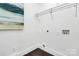 Bright laundry room with white walls, brown floors, utility hookups, wire shelving, and an ocean-themed painting at 2038 Sandhurst Dr, Charlotte, NC 28205