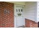 Close-up of front door with decorative accents, set within brick facade and white siding at 205 Gamble Ave, Bessemer City, NC 28016