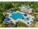 Aerial view of a large community pool with a slide, umbrellas, and a multi-story building surrounded by lush greenery at 2052 Donaldson St, Indian Land, SC 29707