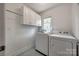 Bright laundry room featuring a modern washer and dryer set with overhead cabinet storage at 2470 Highway 557 Rd, Clover, SC 29710