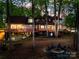 Evening view of the home's backyard featuring a fire pit and multi-level deck illuminated by warm lighting at 252 Greyfriars Rd, Mooresville, NC 28117