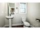 Charming half bath featuring a pedestal sink, a framed mirror, and a window for natural light at 2676 Poplar Cove Nw Dr, Concord, NC 28027