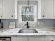 Close up of a kitchen sink with white cabinets, granite countertops, and a window overlooking the outdoors at 3018 Corinth Church Rd, Monroe, NC 28112