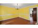 Bright dining room featuring hardwood floors, yellow walls, white trim and chandelier lighting at 469 Augusta Dr, Statesville, NC 28625