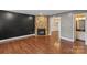 Living room with stone fireplace, dark accent wall, hardwood floors, and view into dining area at 485 Camrose Ne Cir, Concord, NC 28025