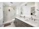 Modern bathroom with double sinks, a large backlit mirror, and glass enclosed shower with marble surround at 6147 Lake Providence Ln, Charlotte, NC 28277