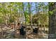 Secluded backyard with fire pit, wooden deck, and lush trees, creating a perfect oasis for relaxation at 7798 Sand Trap Ln, Stanley, NC 28164