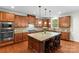 Well-lit kitchen with granite countertops, island with bar stools, stainless steel appliances, and hardwood floors at 7798 Sand Trap Ln, Stanley, NC 28164