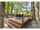 Wooden deck with outdoor dining and seating area amongst the trees at 7798 Sand Trap Ln, Stanley, NC 28164