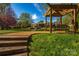 A serene backyard with a bench under a pergola overlooking a pond at 819 Beauhaven Ln, Waxhaw, NC 28173