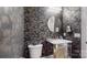 Stylish half bathroom with elegant wallpaper, a round mirror, and marble vanity at 819 Beauhaven Ln, Waxhaw, NC 28173